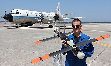 Lead author Joe Cione of NOAA's hurricane research division holds a Coyote sUAS. The drones are being launched into hurricanes from the P-3 hurricane hunter aircraft in the background.