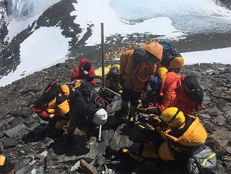 An AWS being installed. Note the tents of Camp IV in the background, and the exposed glacier ice visible behind. Photo credit: Baker Perry / National Geographic.