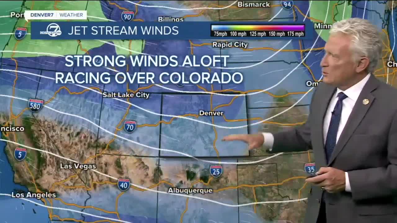 Broadcast meteorologist Mike Nelson wearing a suit, standing in front of a computer simulation of Colorado with a diagram of the jet stream and the caption labeled "Strong Winds Aloft Racing Over Colorado"
