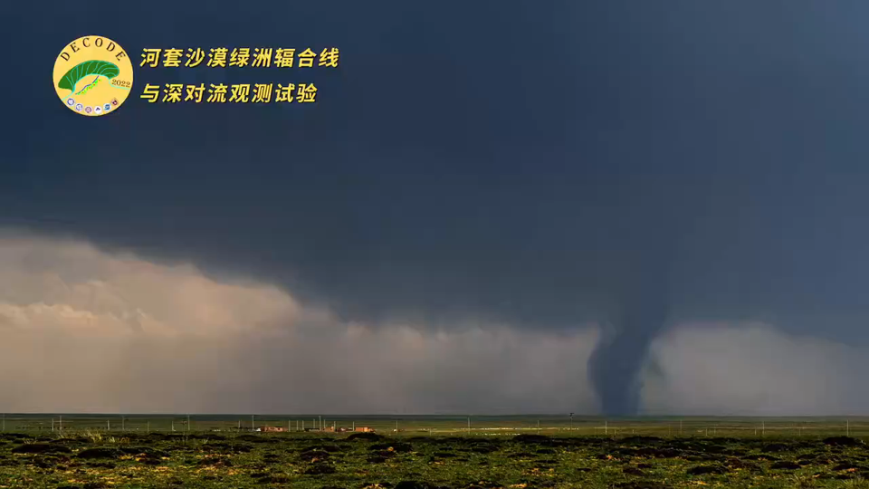 Video still with green agricultural fiels and dark storm clouds in the background. A tornado funnel cloud is seen in the right side of the image. The DECODE project logo appears at the top left.
