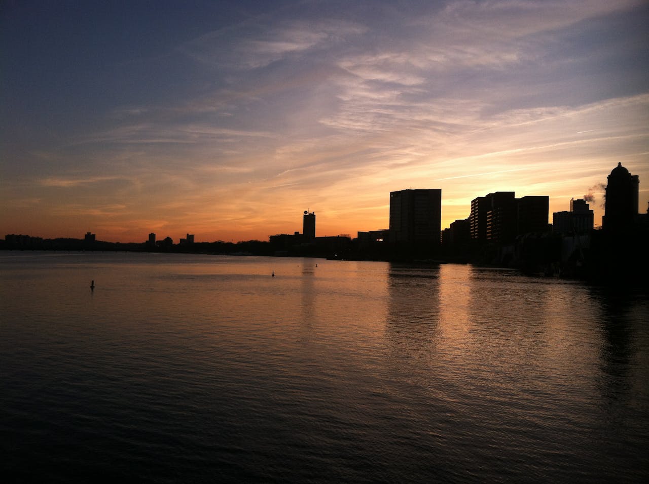 Buildings on a Boston waterfront, silhouetted against a setting sun. Photo by Kristin Vogt on Pexels: https://www.pexels.com/photo/silhouette-photograph-of-buildings-near-calm-body-of-water-17632/